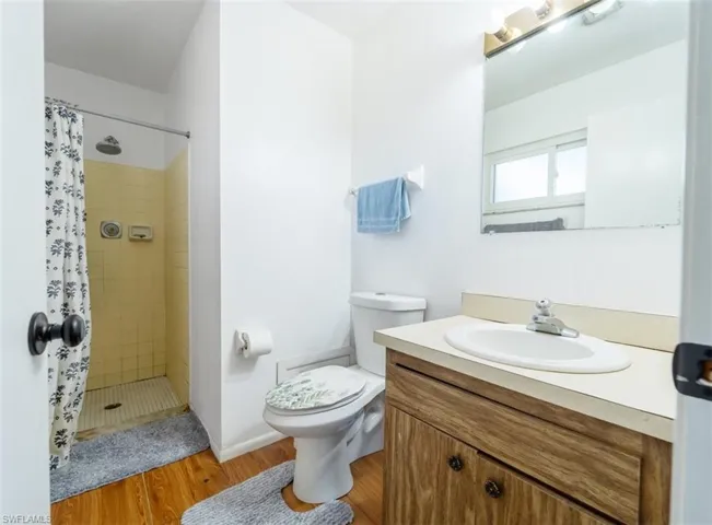 Full bathroom with a stall shower, vanity, and light wood-style flooring