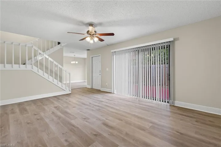Unfurnished room with ceiling fan with notable chandelier, hardwood / wood-style floors, and a textured ceiling
