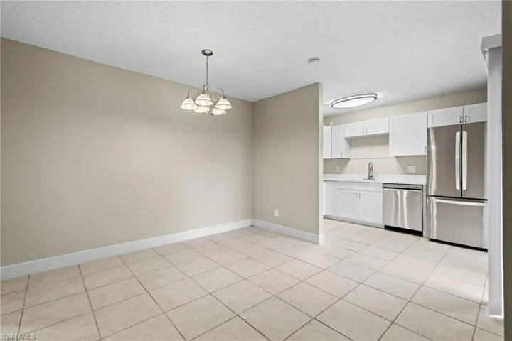 Kitchen featuring light tile patterned flooring, white cabinets, pendant lighting, and stainless steel appliances