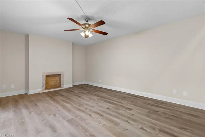 Unfurnished living room featuring a textured ceiling, hardwood / wood-style flooring, and ceiling fan