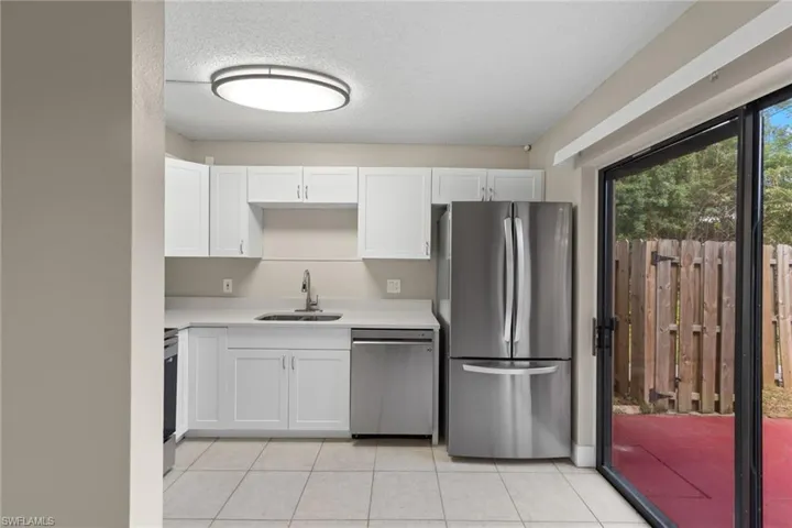 Kitchen featuring appliances with stainless steel finishes, sink, a textured ceiling, light tile patterned flooring, and white cabinetry