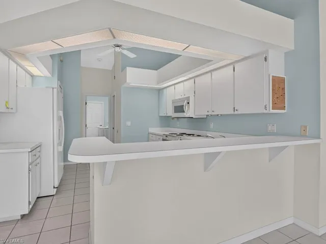 Kitchen with white cabinetry, tile flooring, and a breakfast bar