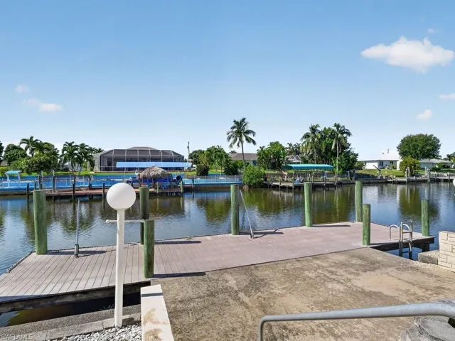 Waterfront property featuring a wood-finish dock, concrete boat ramp, and multiple pilings