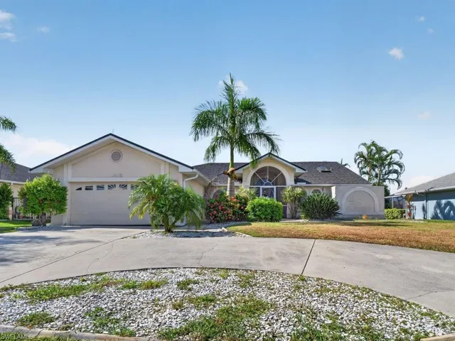 Stucco exterior with a pitched roof, screened arched entry, and an attached garage