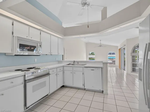 Kitchen featuring white cabinetry, white countertops, built-in microwave, and tile flooring