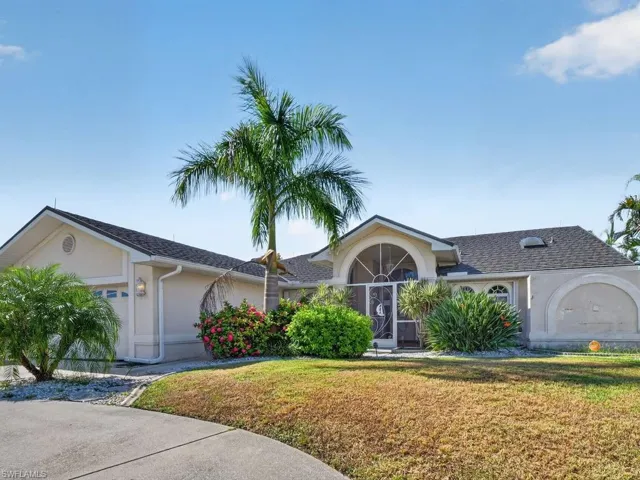 Stucco exterior with a screened entry, arched windows, and an attached two-car garage
