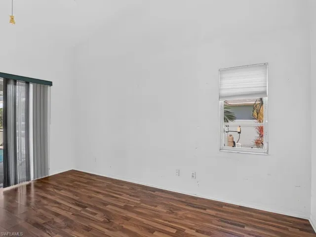 Vaulted ceiling with a ceiling fan, wood-finish flooring, and a sliding glass door