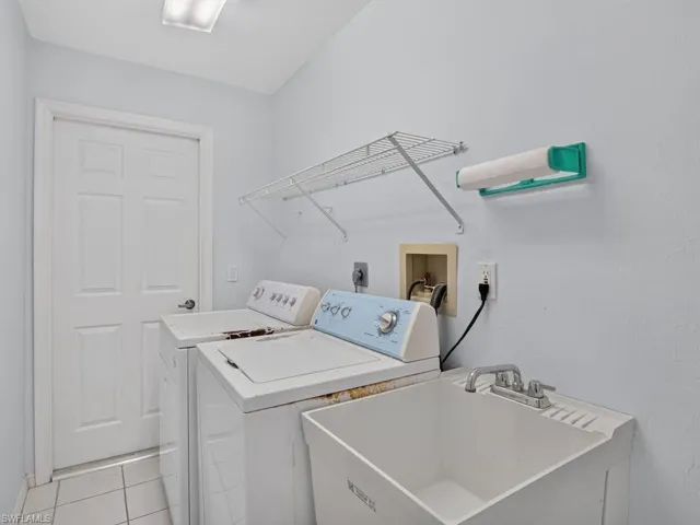 Integrated laundry space featuring a utility sink, overhead wire shelving, and tiled flooring