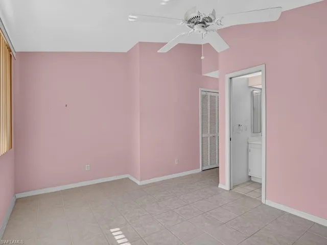 Vaulted ceiling with a ceiling fan, tile flooring, window with vertical blinds, and a louvered bifold door
