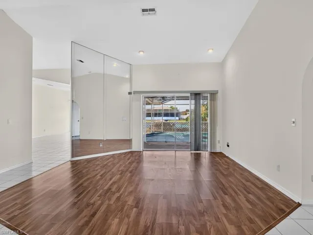 Wood-finish flooring, vaulted ceilings, recessed lighting, mirrored wall, and sliding glass doors