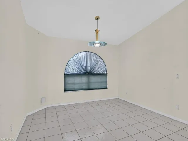 Arched window with privacy blinds, overhead pendant lighting, and neutral-toned walls