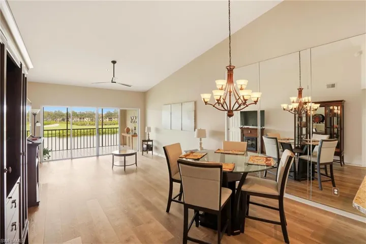 Dining area featuring light wood-style floors, high vaulted ceiling, a chandelier, and a ceiling fan