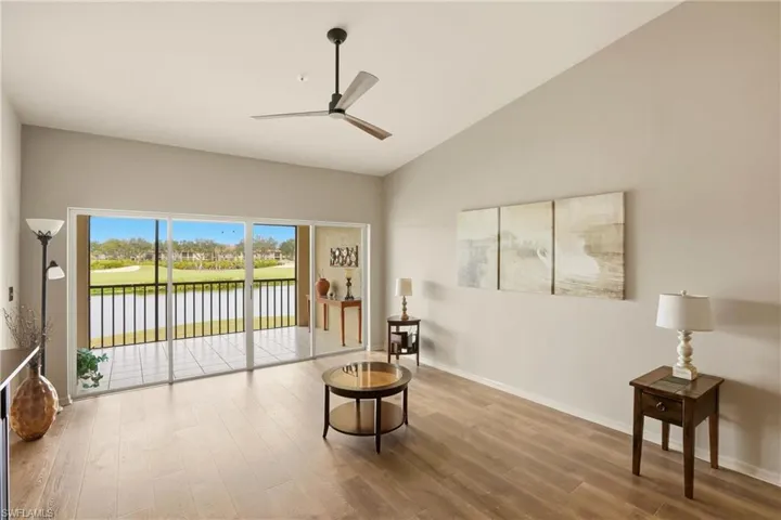 Living area featuring wood finished floors, a ceiling fan, vaulted ceiling, and a water view