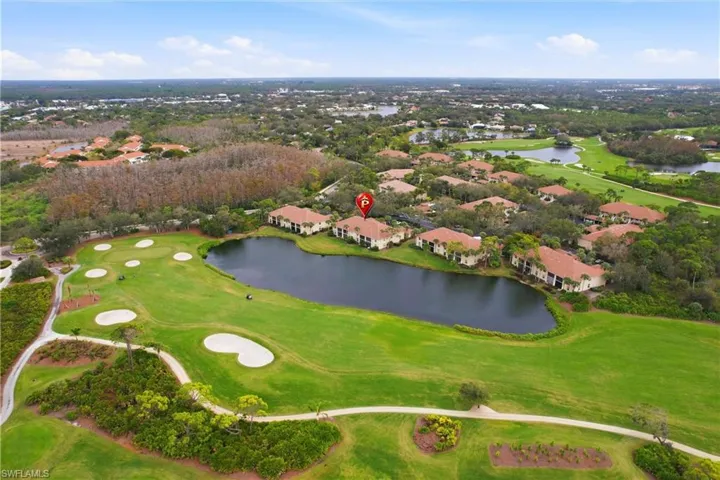 Aerial view of property's location featuring a local golf course, a large body of water, and nearby suburban area