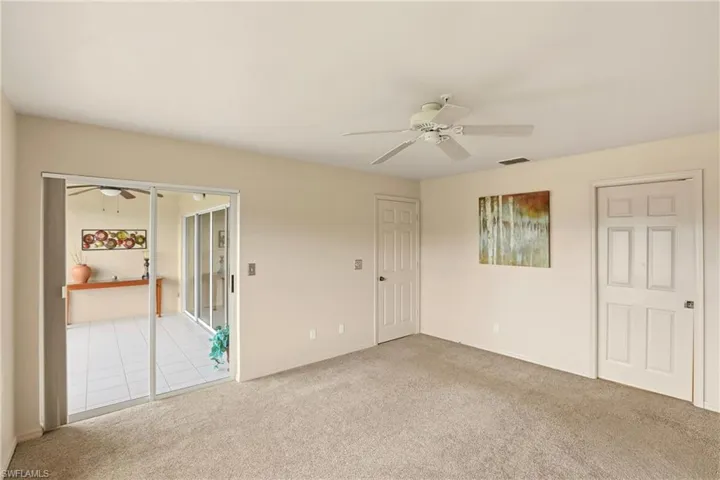 Unfurnished bedroom featuring light carpet and view of lake and golf course
