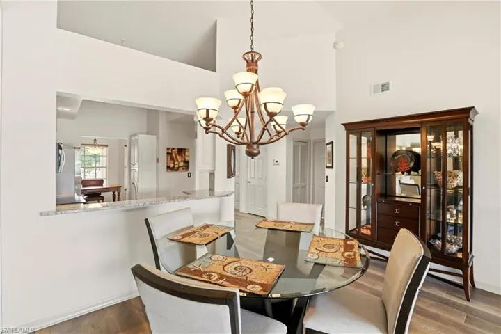 Dining space with high vaulted ceiling, a chandelier, and display cabinet