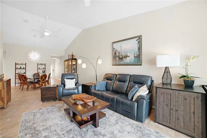 Living room featuring lofted ceiling, light tile patterned floors, and ceiling fan