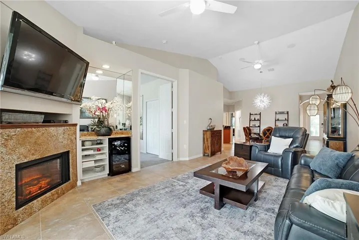 Living room featuring light tile patterned flooring, vaulted ceiling, and ceiling fan