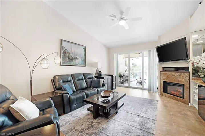 Living room with light tile patterned flooring, lofted ceiling, and ceiling fan