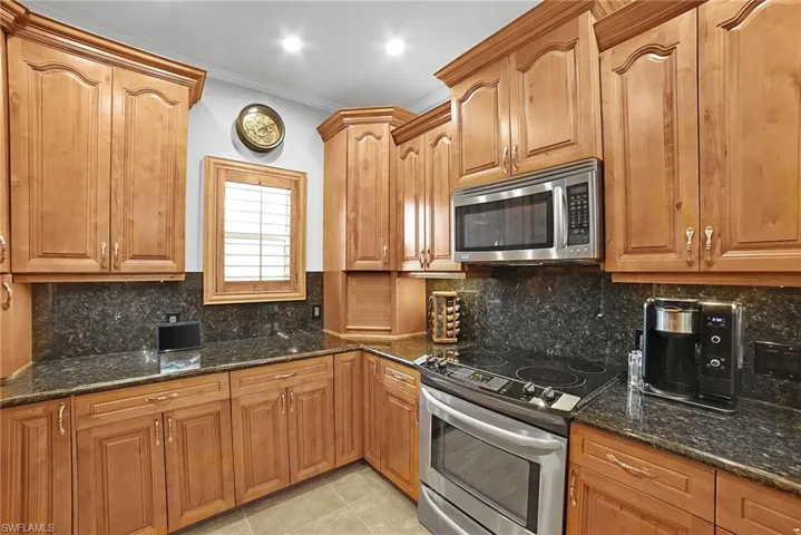 Kitchen with dark stone counters, backsplash, and stove