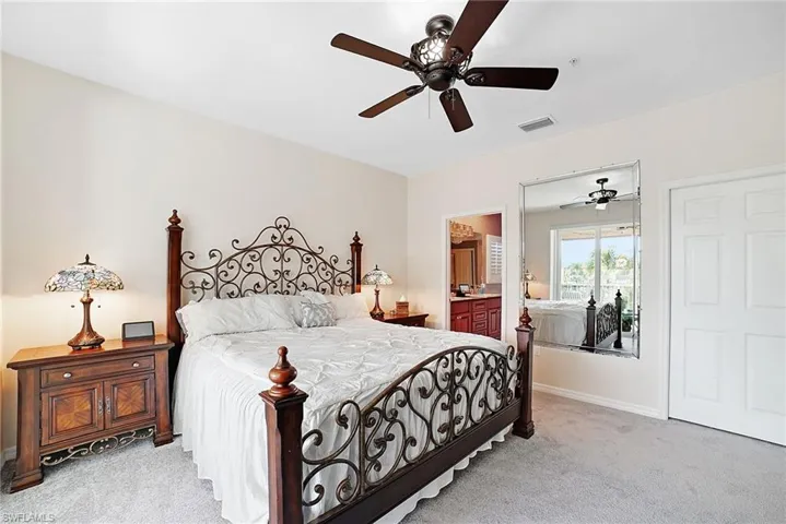 Bedroom featuring light colored carpet, ensuite bathroom, and ceiling fan
