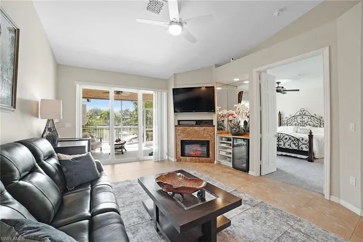 Living room featuring ceiling fan, vaulted ceiling, and light tile patterned floors