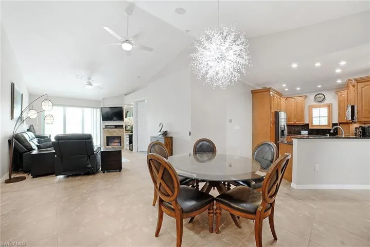 Tiled dining room featuring sink, ceiling fan with notable chandelier, and lofted ceiling