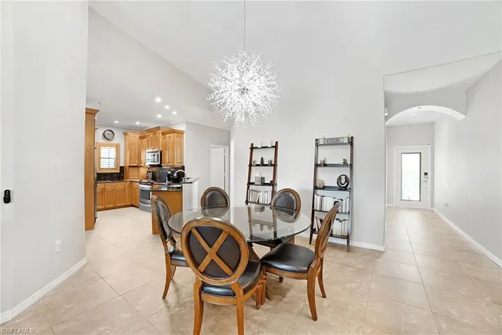 Dining area with vaulted ceiling, a notable chandelier, a healthy amount of sunlight, and light tile patterned floors