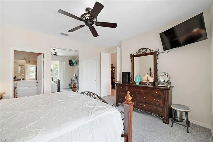 Bedroom featuring ensuite bath, ceiling fan, and light colored carpet