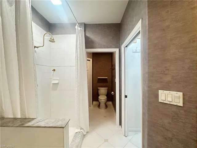 Bathroom with tile patterned floors, a shower with curtain, and toilet
