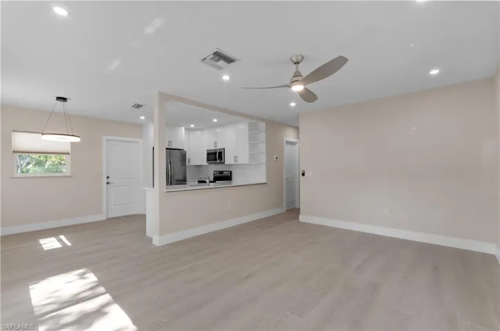open floor plan with  living room, dining and kitchen. tile wood floors, recessed lights and ceiling fan and chandelier.