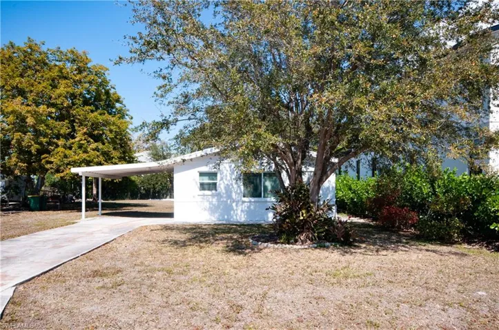View of home's exterior with driveway, a carport, and a yard