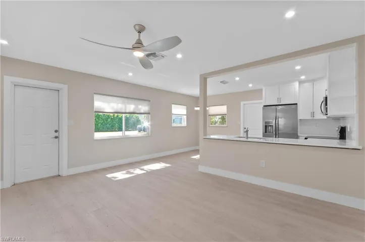 Kitchen featuring white cabinetry, stainless steel appliances, light wood-type flooring, a peninsula, and open floor plan