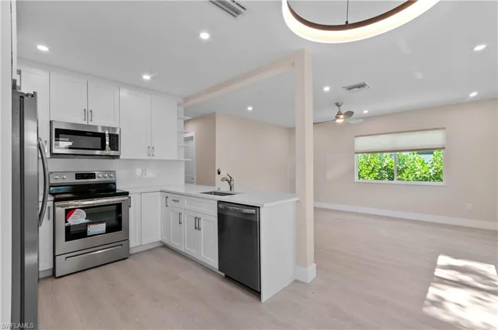 Kitchen with open shelves, stainless steel appliances, open floor plan, white cabinetry, and recessed lighting
