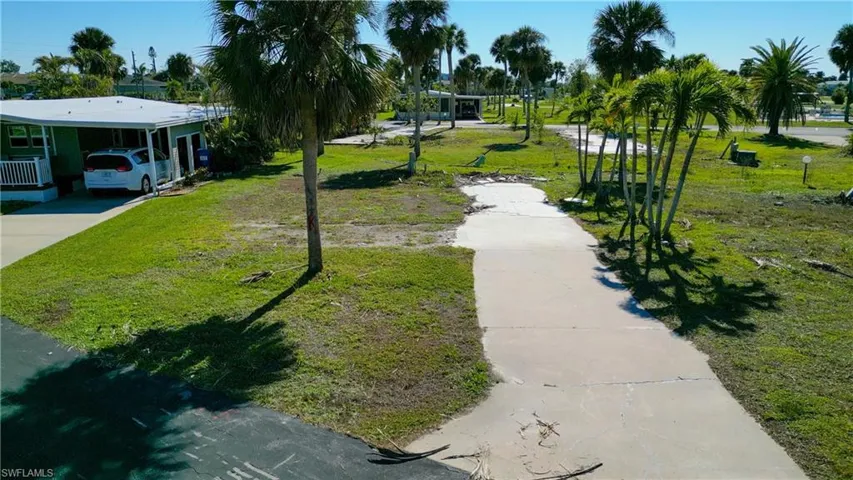 View of community featuring a lawn, a carport, and concrete driveway