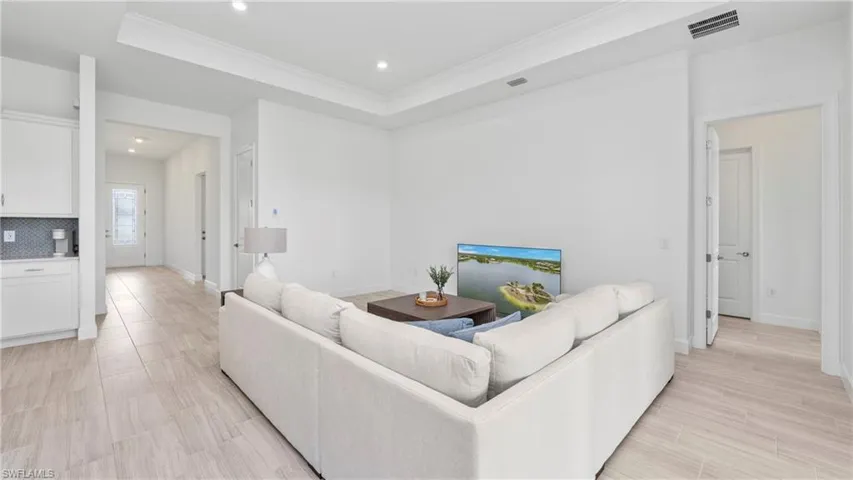Living area featuring a tray ceiling, ornamental molding, recessed lighting, and wood finish floors