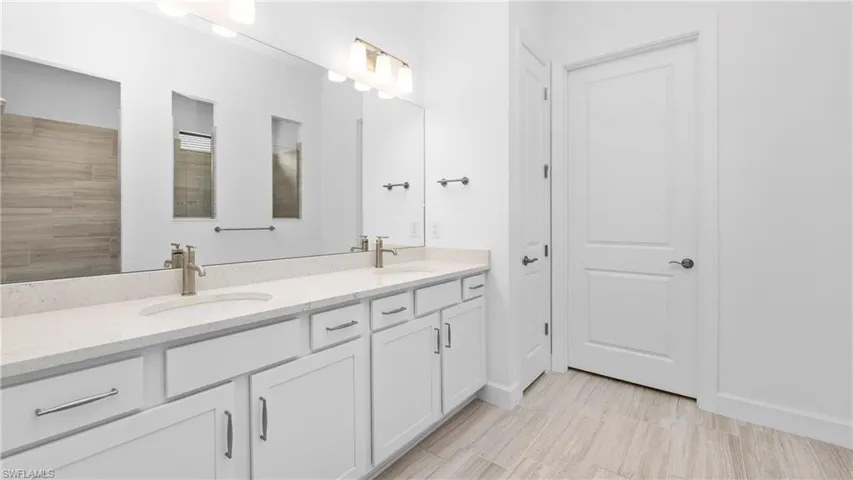 Full bathroom featuring double vanity and baseboards