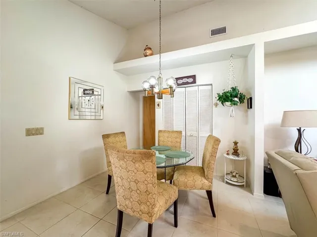 Dining space featuring a high ceiling, a notable chandelier, and light tile patterned flooring
