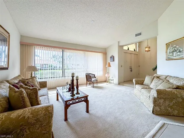 Carpeted living room with a textured ceiling and a notable chandelier