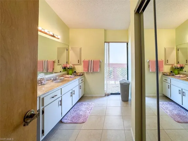Bathroom with tile patterned flooring, vanity, and a textured ceiling