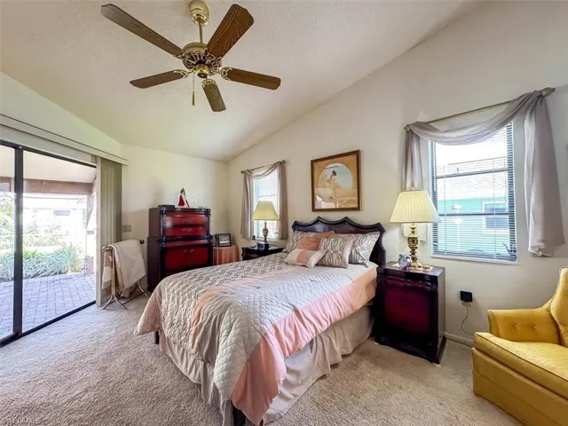 Bedroom featuring light carpet, access to outside, vaulted ceiling, ceiling fan, and a textured ceiling
