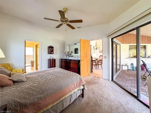 Carpeted bedroom featuring access to outside and ceiling fan with notable chandelier