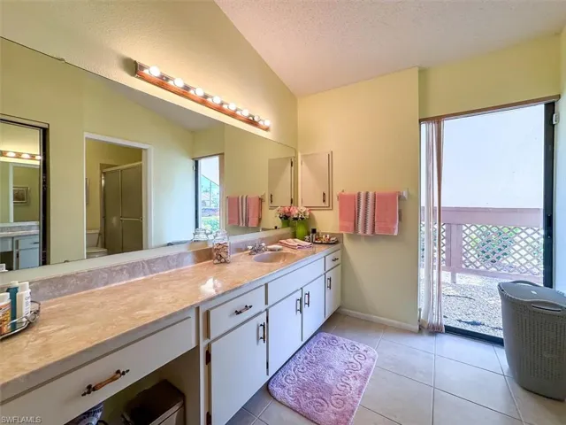 Bathroom featuring tile patterned flooring, plenty of natural light, a textured ceiling, and vaulted ceiling