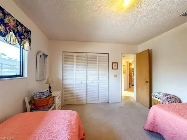 Bedroom featuring a textured ceiling, light colored carpet, and a closet
