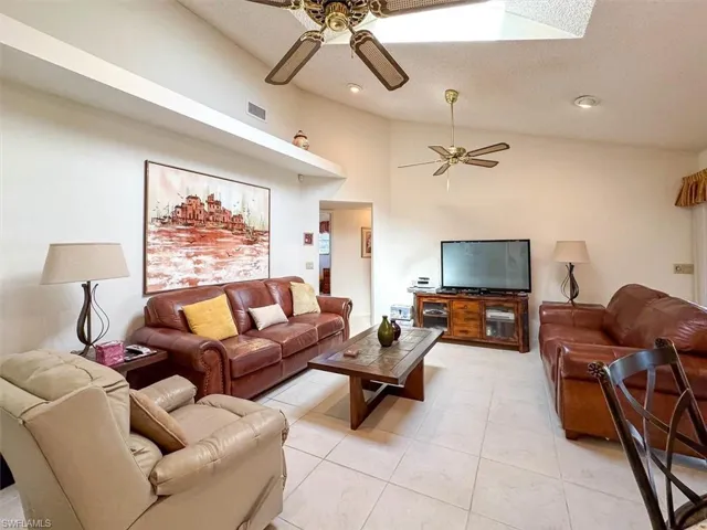Living room featuring ceiling fan, light tile patterned floors, and high vaulted ceiling