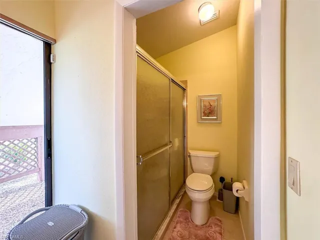 Bathroom featuring toilet, a shower with door, and tile patterned flooring