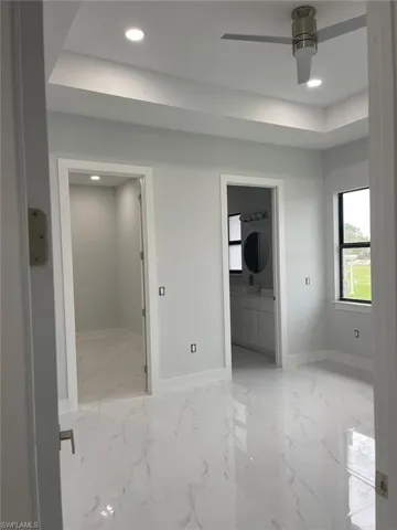 Tiled spare room with sink, ceiling fan, and a tray ceiling