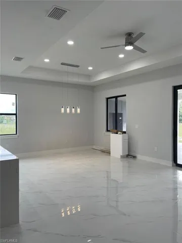 Tiled spare room featuring a raised ceiling and ceiling fan