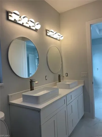 Bathroom with double vanity, tile patterned floors, and toilet