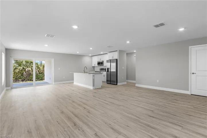 Unfurnished living room with baseboards, recessed lighting, light wood-type flooring, and a sink